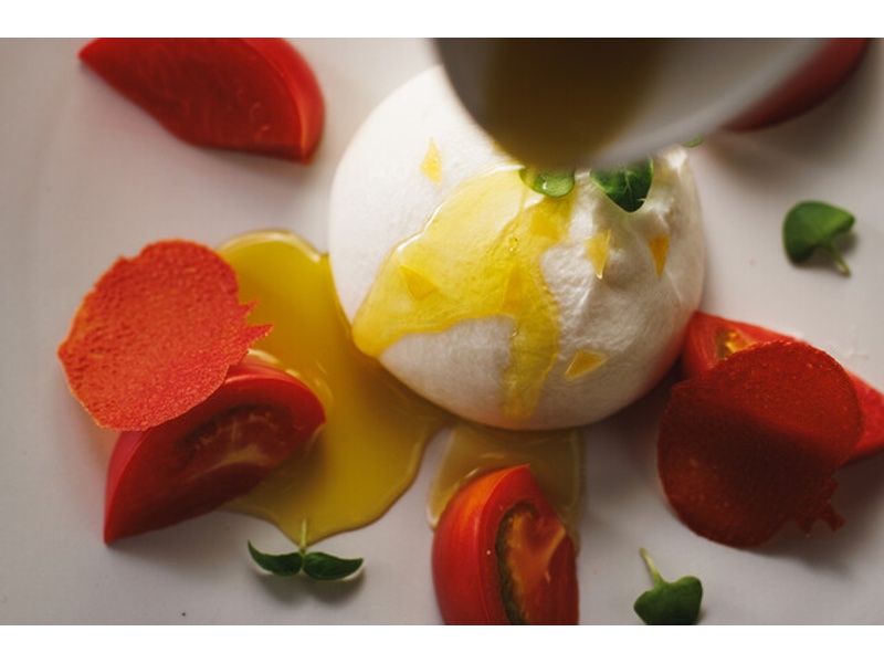 みずみずしいトマトと白いチーズを組み合わせた、色鮮やかな前菜。旬の食材を活かしたシェフこだわりの一皿です。