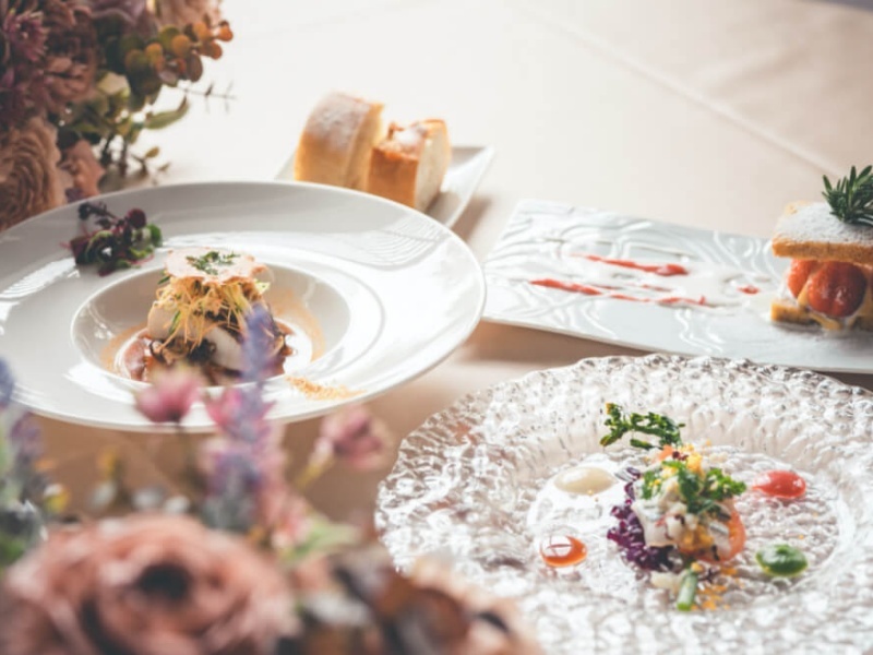 花の装飾に彩られたテーブルに並ぶ、繊細な盛り付けの創作フレンチ。目でも楽しめる美しい一皿が、特別なひとときを演出します。