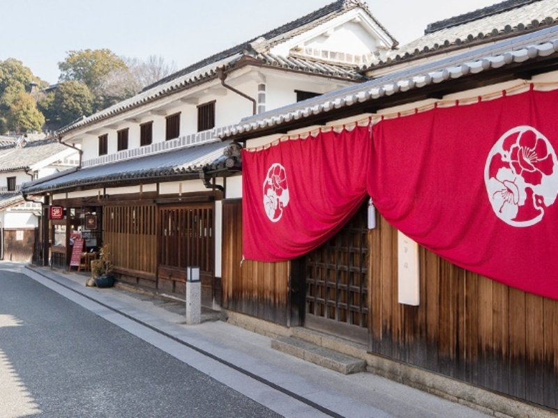 紅い暖簾が揺れる、風情ある町家の外観。美観地区の街並みに溶け込む、華紋ならではの佇まいです。